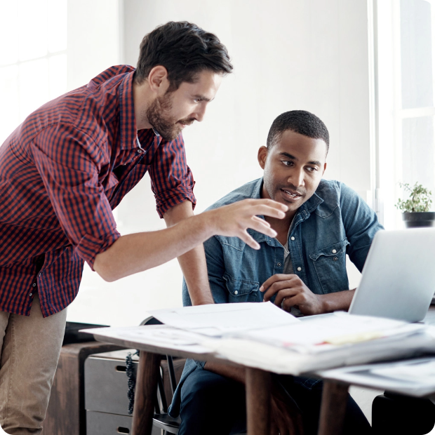 man explaining something to other man on computer