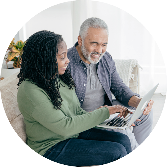 Man and woman sitting on couch looking at computer